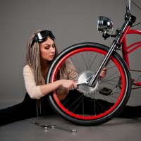 Девушка ремонтирует красный велосипед