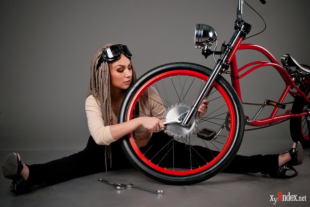Девушка ремонтирует красный велосипед