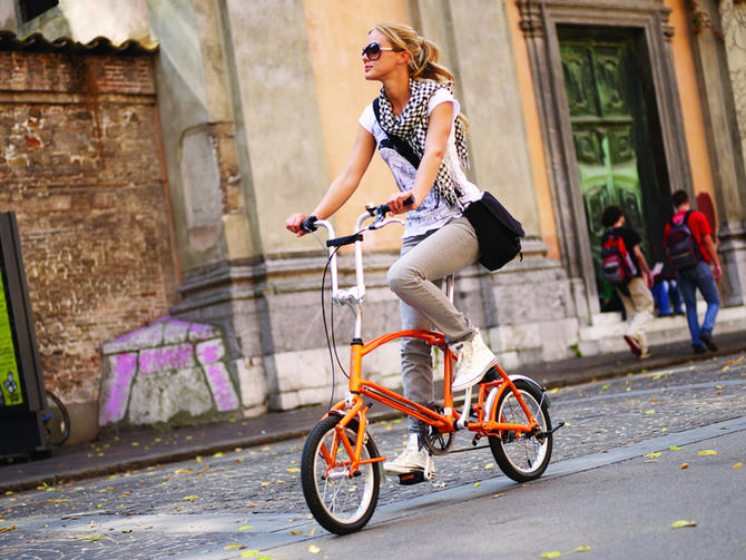 Девушка на оранжевом складном велосипеде