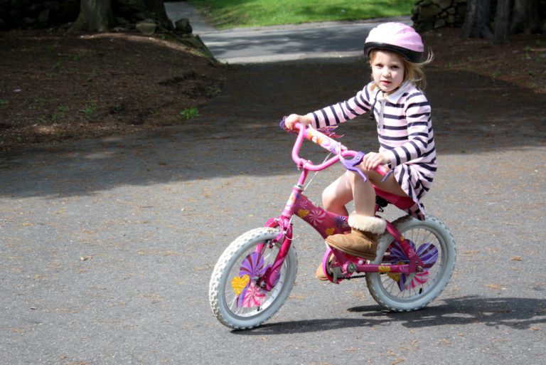 Девочка в шлеме на розовом велосипеде