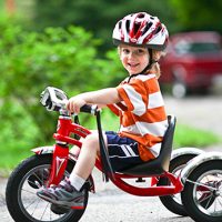 Мальчик на трехколесном красном велосипеде