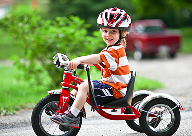 Мальчик на трехколесном красном велосипеде