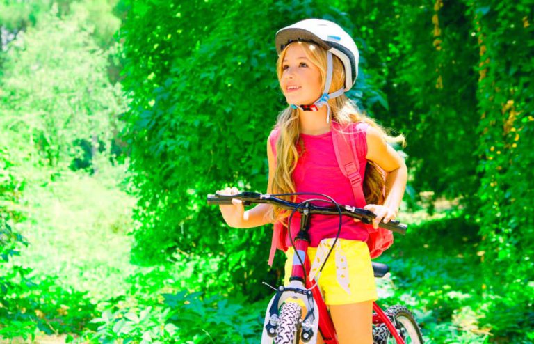 Девочка 12 лет на велосипеде на фоне листвы