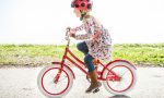 Девочка в шлеме на красном велосипеде с белыми колесами