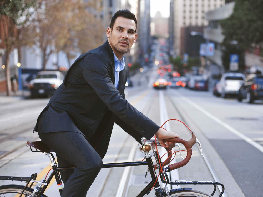 Мужчина в деловом костюме на прогулочном велосипеде