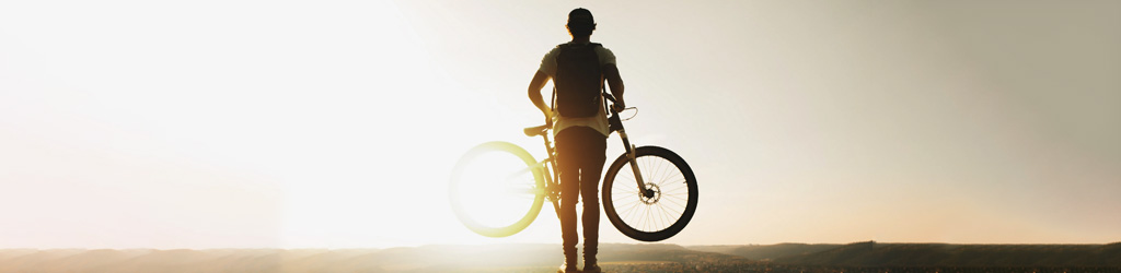 Мужчина с велосипедом на восходе
