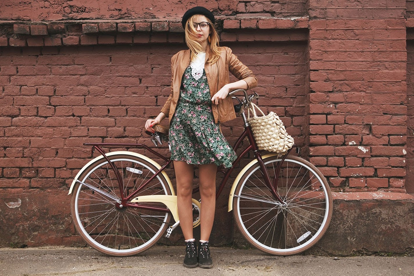 Девушка с велосипедом на фоне кирпичной стены