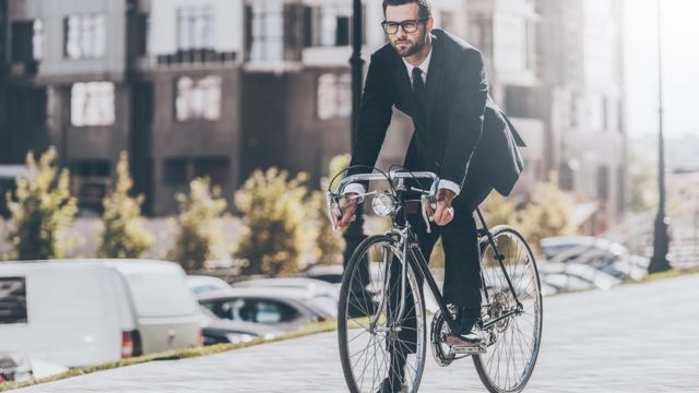 Мужчина в деловом костюме на городском велосипеде