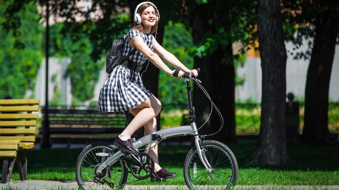 Девушка в парке на складном велосипеде