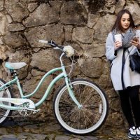 Девушка с городским велосипедом на фоне каменной стены
